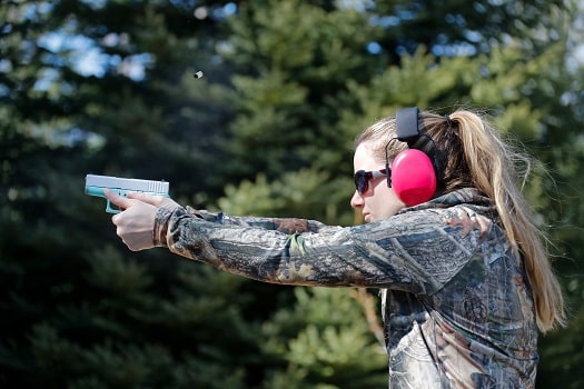 A woman shooting a handgun and the ejected cartridge case in the air
